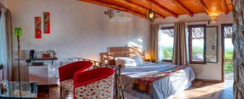 a bedroom with a bed and two red chairs at Tantasiña Cabañas Suites de Montaña in San Javier