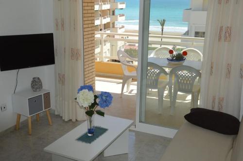 uma sala de estar com uma mesa e vista para o oceano em Apartamento céntrico en la playa con piscina. em Peníscola