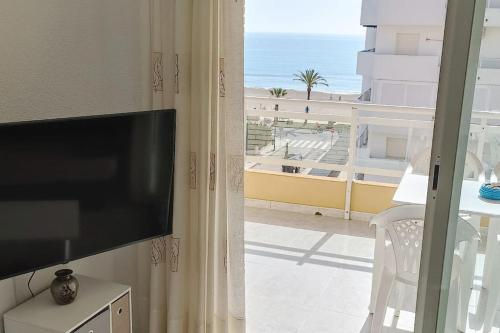 uma sala de estar com televisão e vista para a praia em Apartamento céntrico en la playa con piscina. em Peníscola