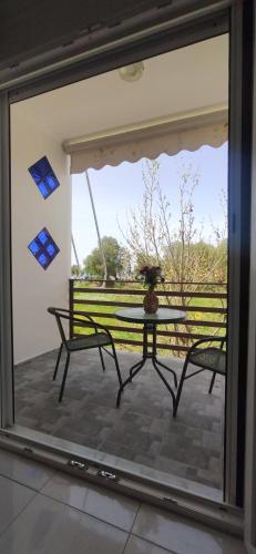 a glass window of a patio with a table and chairs at Kostas Apartments in Kourouta