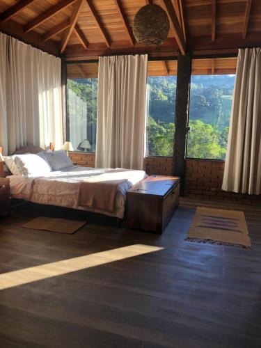 a bedroom with a large bed and large windows at Sítio Mutandis in Itamonte