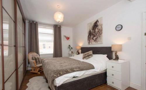 a bedroom with a bed and a chair and a clock at Beautiful 5 bedroom house in great location. in Spon End