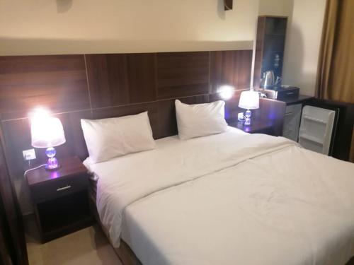 a bedroom with a large white bed with two lamps at Nice View Hotel فندق الأطلالة الجميلة للعائلات فقط in Aqaba
