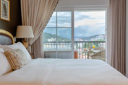 a bedroom with a bed and a large window at Villa do Vale Boutique Hotel in Blumenau