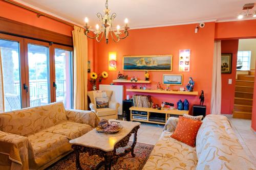 a living room with orange walls and a couch and a table at Villa Mariellie in Néa Péramos