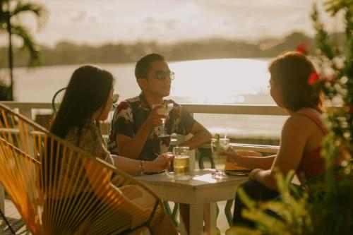 un grupo de personas sentadas en una mesa con bebidas en Hotel Petén Express, en Flores