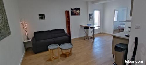 uma sala de estar com um sofá preto e uma mesa em charmant F2 entre Bastia et St Florent em Biguglia