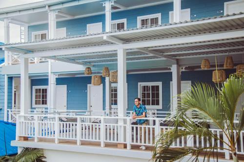 Un uomo in piedi sul portico di una casa blu di Hotel Casona del Lago a Flores