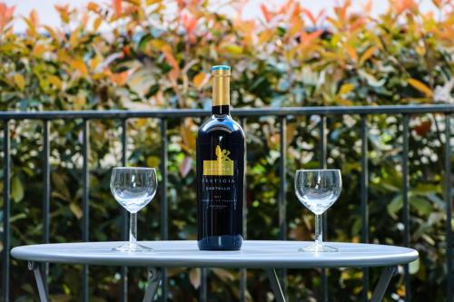 una bottiglia di vino su un tavolo con due bicchieri da vino di Studio apartmani GITA GARDEN a Dubrovnik