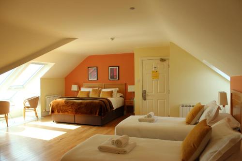 a bedroom with two beds and an orange wall at Inch Beach House B&B in Inch