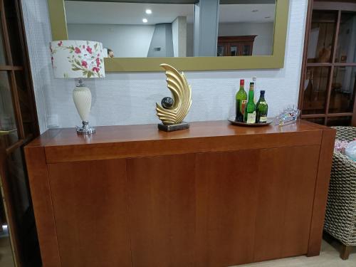 a wooden dresser with bottles of wine and a mirror at Casa Amarela da Caniçada in Vieira do Minho
