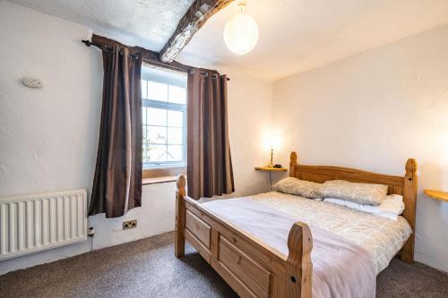 um quarto com uma cama de madeira e uma janela em Cragg Cottage em Lindale