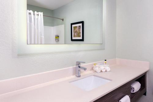 a white bathroom with a sink and a mirror at Holiday Inn Express Hotel & Suites Bonita Springs/Naples by IHG in Bonita Springs