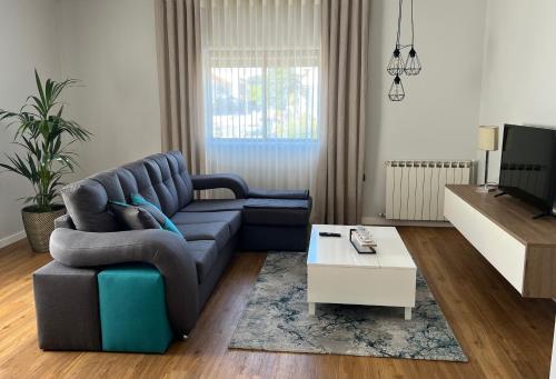 a living room with a blue couch and a tv at Casa das Flores I in Paredes de Coura
