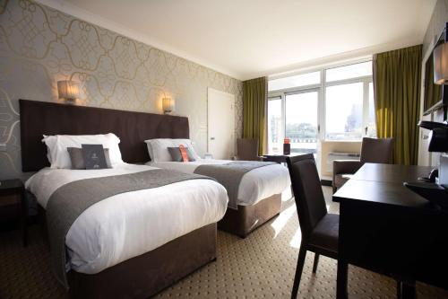 a hotel room with two beds and a desk at The Lincoln Hotel in Lincoln