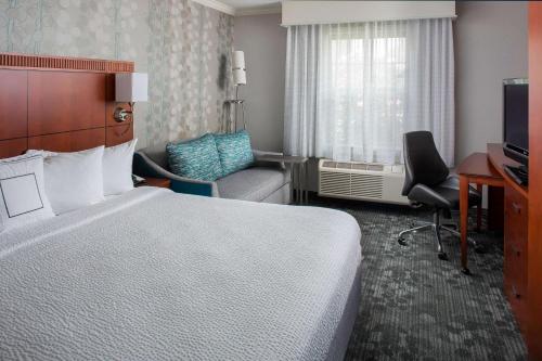ローウェルにあるSonesta Select Boston Lowell Chelmsfordのベッドと椅子付きのホテルルーム