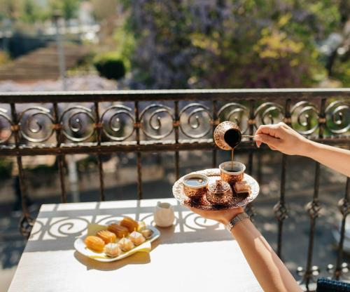 a person holding a cup of coffee and a plate of pastries at Hotel - Villa Lejla in Mostar