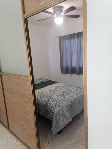 a mirror in a bedroom with a bed and a ceiling fan at Hermoso departamento en Mazatlán in Mazatlán