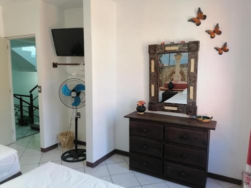 a bedroom with a dresser with a mirror and butterflies on the wall at Casa los Arcos Oaxaca in Oaxaca City