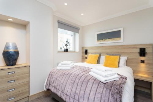 a bedroom with a large bed with yellow pillows at The Barclay Apartment in Perth