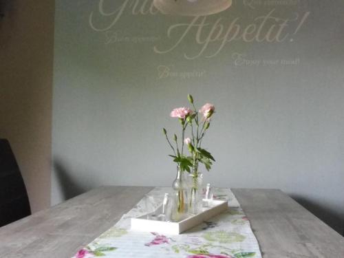 a vase with pink flowers sitting on a table at Apartment with terrace and pool in the garden in Pracht