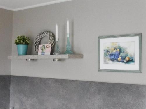 a shelf with two candles and a picture on a wall at Apartment with terrace and pool in the garden in Pracht