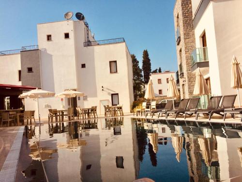a pool in front of a building with chairs and umbrellas at Orya Aparts in Gümbet