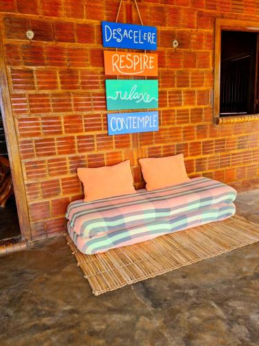 a bed sitting against a brick wall with a sign at Casa da Peroba Sol - Pé na Areia - Praia da Peroba - Icapuí in Icapuí