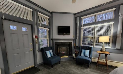 a bedroom with two blue chairs and a fireplace at Blackberry Inn in Camden