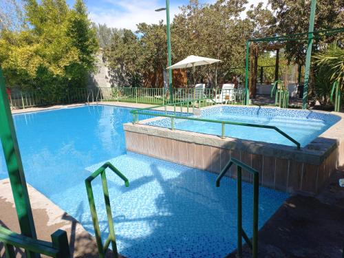 a large swimming pool with two chairs and an umbrella at Cabañas Atahualpa in Pica