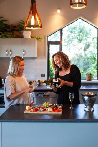 two women standing in a kitchen pouring wine at Orokawa Bay Retreat in Waihi