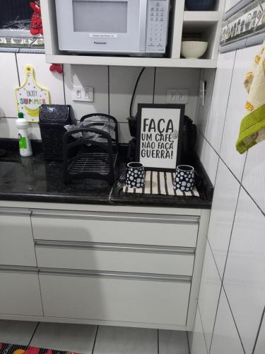 a kitchen counter with a microwave on top of it at Apto Top Boqueirão Praia Grande. in Praia Grande