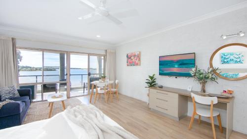 a living room with a bed and a desk and chairs at Moby Dick Waterfront Resort Motel in Yamba