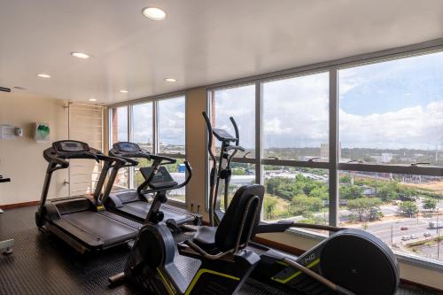 a gym with three cardio machines in front of a large window at Holiday Inn Manaus by IHG in Manaus