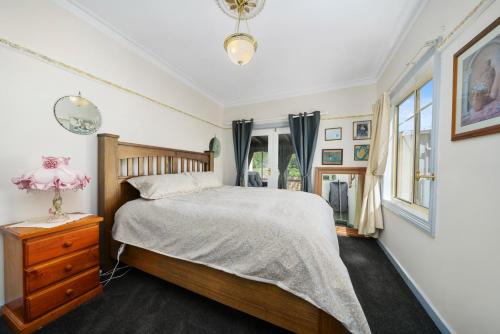 ein Schlafzimmer mit einem Bett, einer Kommode und einem Fenster in der Unterkunft Haere'mai House in New Norfolk