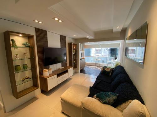 a living room with a couch and a television at Apartamento com 3 dormitórios in Balneário Camboriú