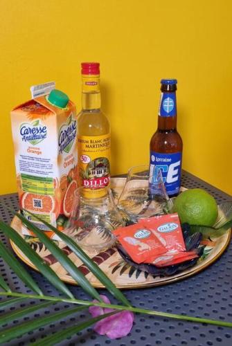 a plate with food and drinks on a table at Appartement 2 chambres, avec jardin, grande terrasse, Barbecue, 8 min du centre ville in Fort-de-France