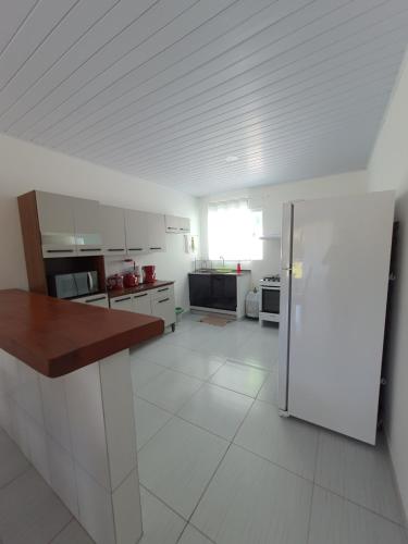 a large kitchen with white cabinets and a refrigerator at Chalés Cantinho Da Mary in São Miguel dos Milagres