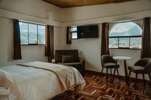 a bedroom with a bed and a table and chairs at Atusparia Guest House Huaraz in Huaraz