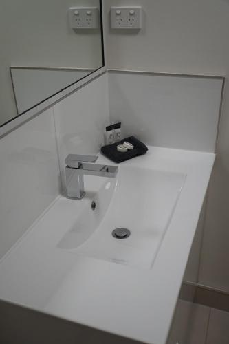 a white bathroom with a sink and a mirror at Airlie Seaview Apartments in Airlie Beach