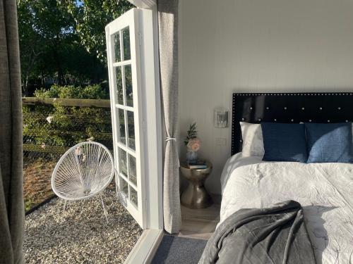 a bedroom with a door open to a balcony with a bed at Farm Stay HARMONY Cottage at Wilindi Estate in Tyabb