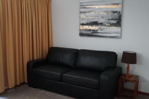a black couch in a living room with a lamp at Airlie Seaview Apartments in Airlie Beach