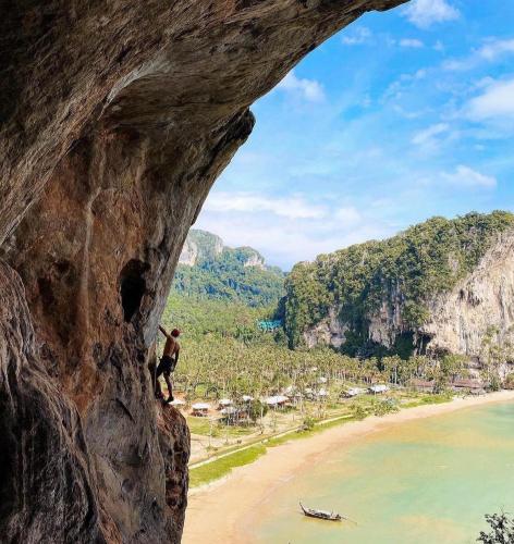 a man standing on a cliff looking out at a beach at Tinidee Hideaway Tonsai Beach Krabi - SHA Extra Plus in Tonsai Beach