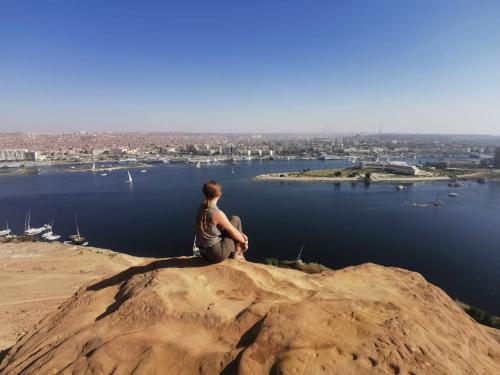 a man sitting on a rock overlooking a body of water at Nuba Narty in Aswan