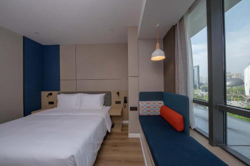 a bedroom with a bed and a couch and a window at Holiday Inn Express Chongqing Caiyun Lake, an IHG Hotel in Chongqing