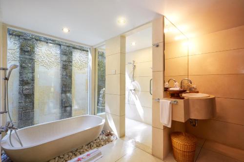a bathroom with a tub and a shower and a sink at Visakha Sanur by Puri Signatures in Sanur