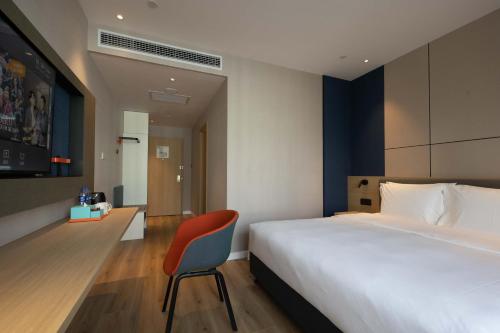 a bedroom with a large bed and a red chair at Holiday Inn Express Chongqing Caiyun Lake by IHG in Chongqing