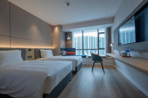 a hotel room with two beds and a desk at Holiday Inn Express Chongqing Caiyun Lake by IHG in Chongqing