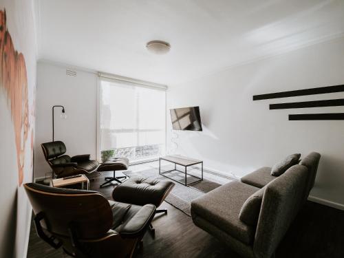 una sala de estar con un sofá y sillas en SoYa Apartment Hotel, en Melbourne