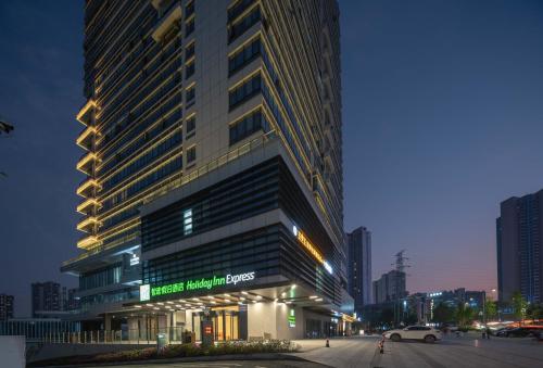 a large building in a city at night at Holiday Inn Express Chongqing Caiyun Lake by IHG in Chongqing